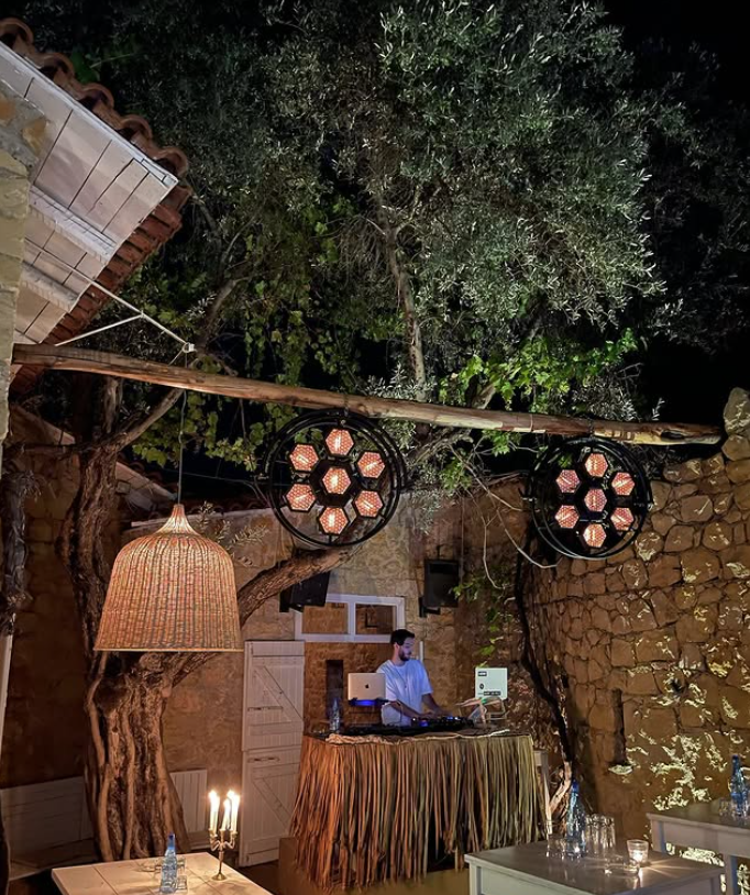 The DJ booth at Alekos — laptop, decks, hexagonal lights under the olive tree